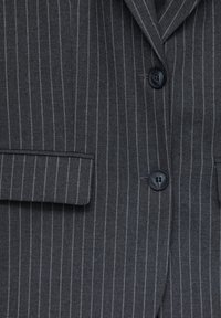 Blazer a rayas grises con solapa muescada, dos botones negros y un bolsillo en el pecho, con una textura suave.