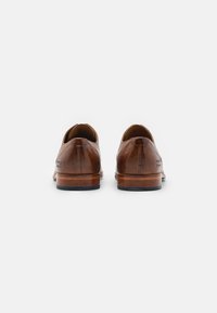 Pantofi din piele maro cu vârf rotund, cusături decorative minime și toc din lemn. Textură netedă și design cu profil scăzut.