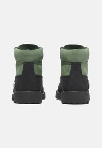 Stivaletti alla caviglia in suede verde e nero con punta arrotondata, colletto imbottito e suola testurizzata. Presentano un accento metallico rotondo sul lato.