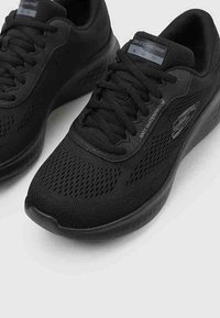Zapatillas negras impermeables con parte superior de malla, detalles texturizados y cierre de cordones. Presentan acentos de logo en los laterales y la lengüeta.