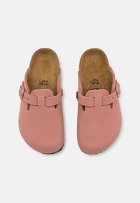 Zoccoli rosa con una superficie superiore in sintetico liscio, dotati di punta rotonda, fibbia laterale e una soletta in sughero testurizzata per il massimo comfort.