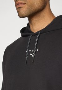 Black hoodie featuring a white logo, drawstrings with a textured pattern, and a soft, smooth fabric. No visible graphics or additional accents.