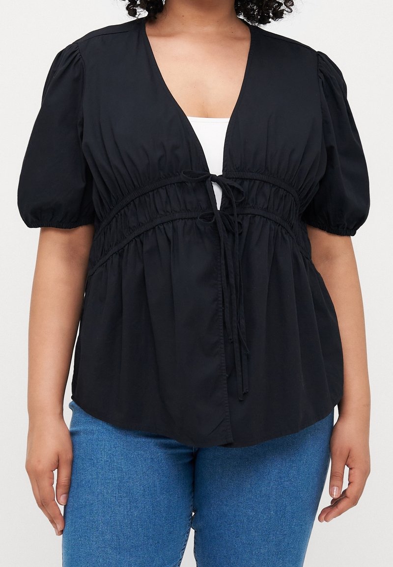 Schwarze kurzärmelige Bluse mit tiefem V-Ausschnitt und elastischem Kordelzugbund; glatte Textur mit gerafften Ärmeln und fließendem Design.