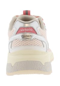Zapatilla con parte superior de malla blanca y rosa claro, acentos metálicos, un cuello acolchado y una suela texturizada en color blanco roto.