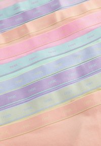 Miękkie, pastelowe tkaninowe paski ułożone w nachodzących na siebie rzędach, każdy z nich tłoczony w subtelny wzór z napisem "next".