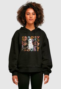 Mustassa hupparissa on sana "SPOOKY" monivärisellä tekstillä. Suunnittelu sisältää keskellä olevan haamu-graafisen kuvaston. Pehmeä kangas, rento malli.