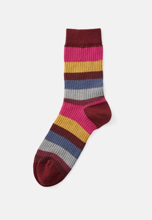 Calzino a righe con texture a costine. I colori includono rosa, giallo, bordeaux, blu, grigio e rosso scuro. Presenta una punta e un tallone rinforzati.