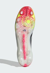 Σόλα παπουτσιού ποδοσφαίρου με διάφανες τάπες, κόκκινο και κίτρινο σχέδιο Predator, και ροζ υποστήριξη Power Spine που διατρέχει το κέντρο.