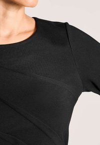 Zwart nauwsluitend topje met een ronde halslijn, gestructureerde stof en diagonale naden, die een gestructureerd ontwerp benadrukken.