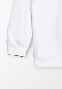 Manica di felpa bianca in cotone con polsini a costine. Tessuto liscio e vestibilità comoda. Nessun motivo o decorazione visibile.