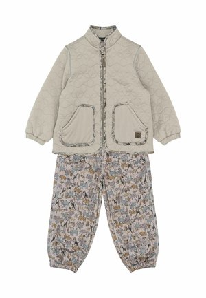 Beżowa pikowana kurtka z dwoma przednimi kieszeniami i wysokim kołnierzem; jasne spodnie z wzorem przedstawiającym różne zwierzęta w stonowanych kolorach.