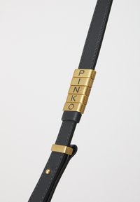 Black leather strap featuring gold hardware with engraved letters spelling "PINKO." Smooth texture with contrasting stitching details.