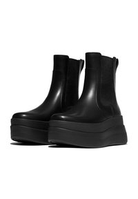 Black platform boots made of smooth leather with elastic side panels and a chunky, raised sole. Sleek design with minimal detailing.