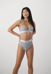 Set gri din amestec de bumbac, format din bralette și chiloți cu talie înaltă. Prezintă benzi elastice albe cu brand. Design simplu și minimalist.