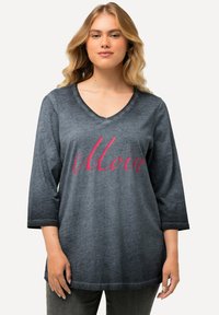 Maglietta grigia a maniche lunghe con scollatura a V, caratterizzata da un effetto gradiente e la scritta "Moin" in bold rosa, realizzata in materiale morbido e con vestibilità rilassata.