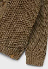 Brauner Strickcardigan mit einem strukturierten Muster, der eine Knopfleiste, gerippte Bündchen und ein kleines Stoffetikett am Saum aufweist.