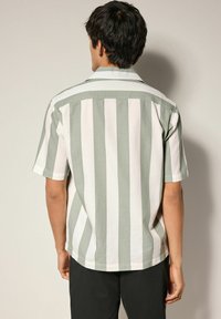 Kurzarmhemd mit abwechselnden grünen und weißen Streifen, strukturiertem Stoff und einem Camp-Kragen sowie einem geschwungenen Saum.