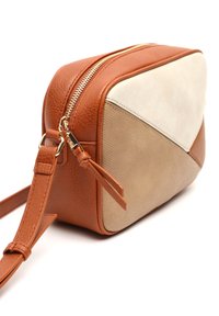 Kozmetická taška v tan a krémové barvě, která je vyrobena z texturované kůže, má zlatý zip a geometrický design s kontrastními materiály a barvami.