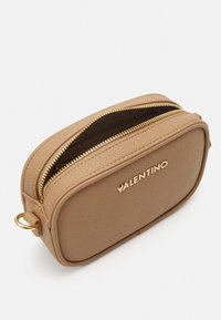 Brūna teksturēta ādas kosmētikas soma ar zelta rāvējslēdzēju, apaļa forma un izspiestā "VALENTINO" logo priekšā.