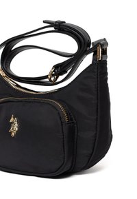 Czarna nylonowa torba na ramię z złotym zamkiem błyskawicznym i elementami, wyposażona w małą przednią kieszeń i akcent z logo. Gładka tekstura i zaokrąglony kształt.