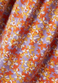 Blumenmuster auf einem helllila Hintergrund in den Farben Orange, Gelb und Weiß, mit kleinen, verstreuten Blumenmustern und einer weichen Textur.