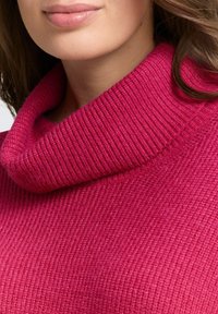 Fuchsia gestrickter Pullover mit hohem, umgeschlagenem Kragen. Die Textur ist gerippt, und der Stoff wirkt weich und gemütlich.