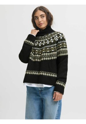 Pull en tricot noir avec un col montant, présentant un empiècement à motifs en blanc et vert. Associé à un jean en denim bleu clair.