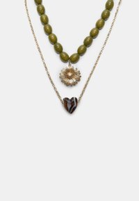 Collana a tre strati con perline verde oliva, un pendente a forma di girasole in oro e un charm a forma di cuore a righe in tonalità scure, il tutto su catene d'oro.