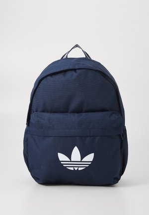 Mochila azul marino con bolsillo delantero con cremallera y logo blanco de Adidas trefoil sobre un fondo claro y liso.