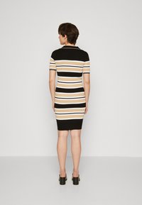 Abito in maglia dal design aderente con strisce orizzontali nere, beige e bianche. Maniche corte e orlo a coste accentuano la silhouette.