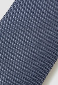 Cravat bleumarin dintr-un material texturat țesut, având un model în rețea. Suprafața este netedă, cu un luciu subtil și o structură fermă.