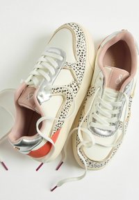 Weiße Leder-Sneaker mit silbernen Akzenten, gepunktetem Muster und pinkem Kragen. Sie verfügen über flache Schnürsenkel, goldene Verzierungen und eine pinke Zunge.