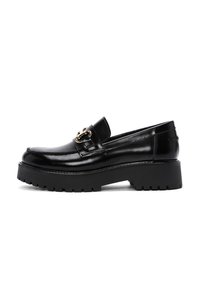 Mocassino in pelle nera con suola in gomma spessa, caratterizzato da un dettaglio in metallo dorato decorativo sulla tomaia e una finitura liscia e lucida.