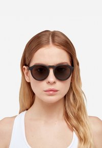 Ümarjad mustad prillid, millel on gradient tumedad läätsed, matist viimistlus ja kaasaegne, minimalistlik disain. Õhuke must raam täiendavad läätsi.