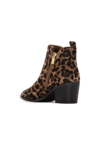 Botas de tobillo con estampado de leopardo en marrón y negro, con un cierre lateral de cremallera y herrajes dorados, y un tacón cuadrado negro de altura media.