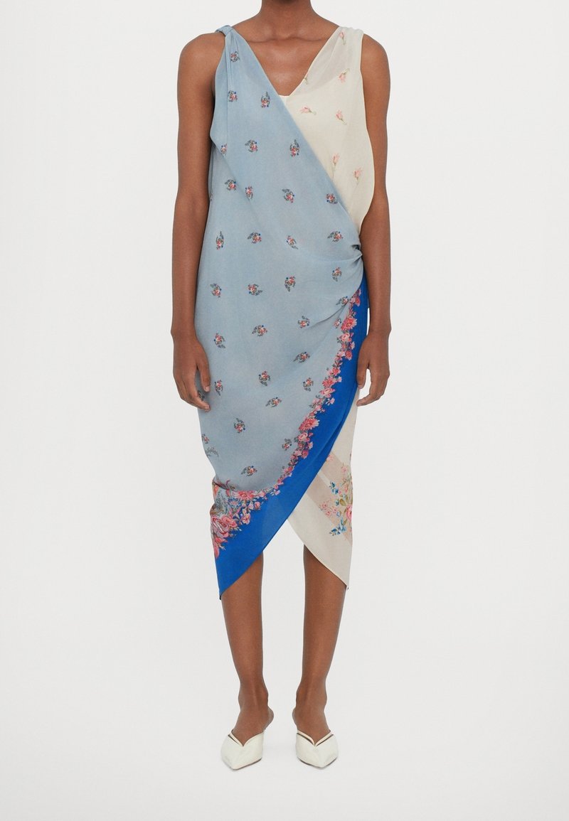 Robe en satin avec un motif bleu, crème et floral, design asymétrique, textures variées et silhouette drapée.