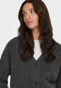 Cardigan grigio antracite realizzato in tessuto morbido; presenta un collo a V, maniche lunghe e due bottoni neri sul davanti.