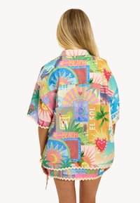 Chemise colorée à manches courtes avec motifs tropicaux, graphiques vibrants et ourlet festonné. Fabriquée en tissu léger, idéale pour les temps chauds.