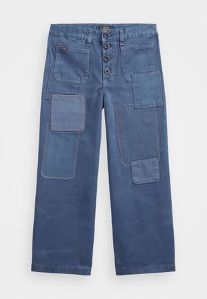 Niebieskie szerokie spodnie z wieloma prostokątnymi łatkami na przodzie, zapięciem na guziki i przednimi kieszeniami naszywanymi oznaczonymi napisem „Polo”.