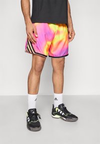 Krátke basketbalové šortky s viacfarebným prechodom od ružovej cez žltú po oranžovú, s čiernymi a bielymi bočnými pásmi. Čierne športové topánky.