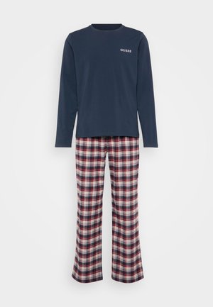 T-shirt de manga longa azul-marinho com o logótipo "GUESS", combinado com calças de pijama em padrão xadrez em vermelho, branco e azul. Tecido suave, corte descontraído, pernas retas.