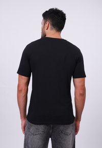 Zwarte katoenen t-shirt met korte mouwen, een ronde halslijn en een eenvoudig ontwerp. Draag met grijze denim jeans.