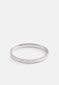 Pulsera de bangle de metal plateado con una superficie lisa y pulida y un logotipo en relieve, con un acento de cuentas a lo largo de los bordes.
