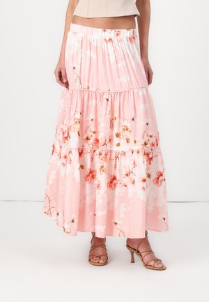 Luchtige lichtroze bloemen midi rok met laagjes gedragen met tan gekleurde sandaaltjes met hoge hakken en een beige cropped top.