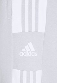 Grauer Sportstoff mit horizontalen weißen Drei-Streifen-Akzenten und einem weißen Adidas-Logo, das ein modernes, sportliches Design schafft.