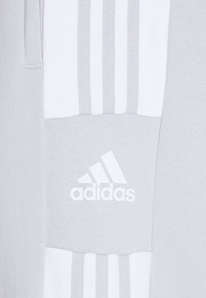Tejido atlético gris con acentos horizontales de tres rayas blancas y un logo blanco de Adidas, creando un diseño moderno y deportivo.