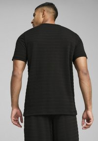 Sort kortærmet t-shirt med et struktureret stribemønster, rund halsudskæring og en afslappet pasform, båret med matchende underdele.