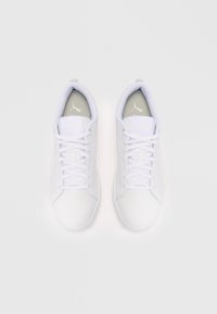 Ein Paar weiße Puma-Sneaker mit Schnürsenkeln, von oben auf einem weißen Hintergrund betrachtet, mit grauen Innensohlen und dem Puma-Logo.