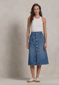 Denim A-linjainen hame korkealla vyötäröllä, jossa on edessä nappikiinnitys ja halkio. Yhdistettynä valkoiseen topiin ja beigeihin lenkkareihin.