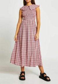 Rosa rutigt mönster på klänning med smockad byst och stor krage. Flödande maxilängd, med korta ärmar och en samlad kjol.